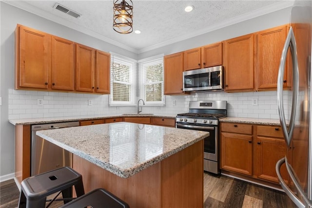 kitchen featuring visible vents, a breakfast bar, dark wood-type flooring, stainless steel appliances, and a sink