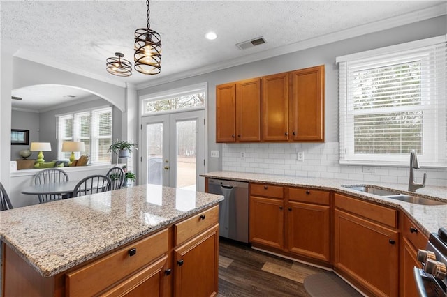 kitchen featuring visible vents, brown cabinets, dark wood-style flooring, stainless steel appliances, and a sink