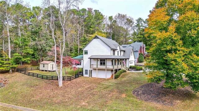 back of property featuring a wooden deck, a yard, and a storage unit