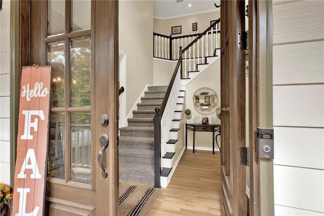 foyer entrance with ornamental molding and light wood-type flooring