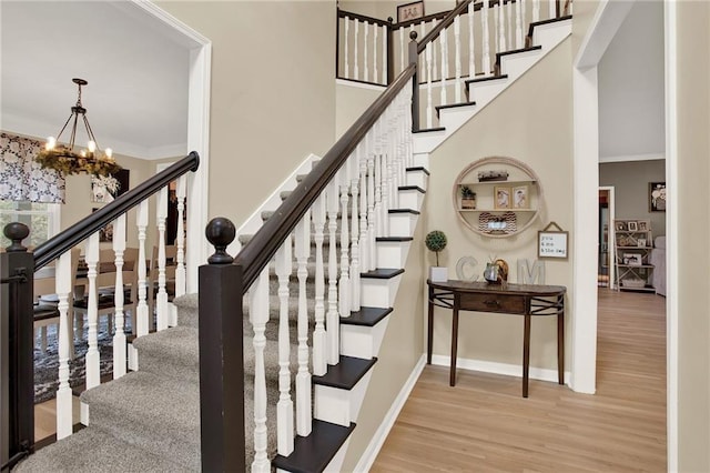 stairway featuring hardwood / wood-style flooring, crown molding, and an inviting chandelier