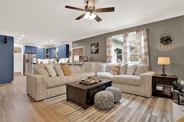 living room featuring ceiling fan, light hardwood / wood-style flooring, and crown molding