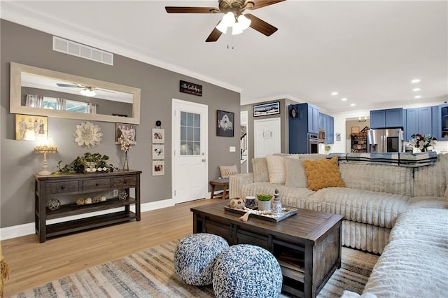 living room with light hardwood / wood-style floors, ceiling fan, and ornamental molding