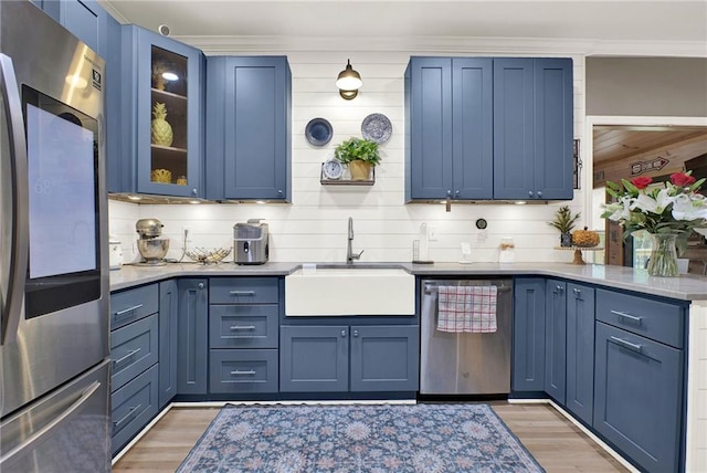 kitchen featuring dark wood-type flooring, blue cabinets, crown molding, sink, and stainless steel appliances