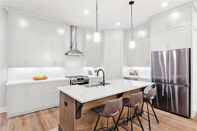 kitchen featuring sink, a kitchen bar, stainless steel appliances, a center island with sink, and wall chimney exhaust hood