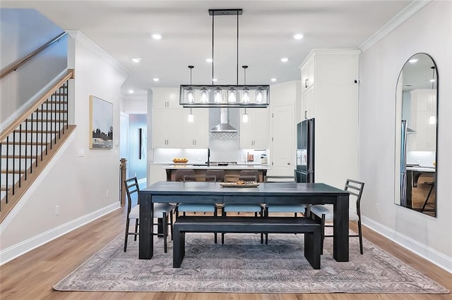 dining space with crown molding and light hardwood / wood-style floors