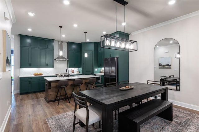 dining space featuring crown molding, wood-type flooring, and sink