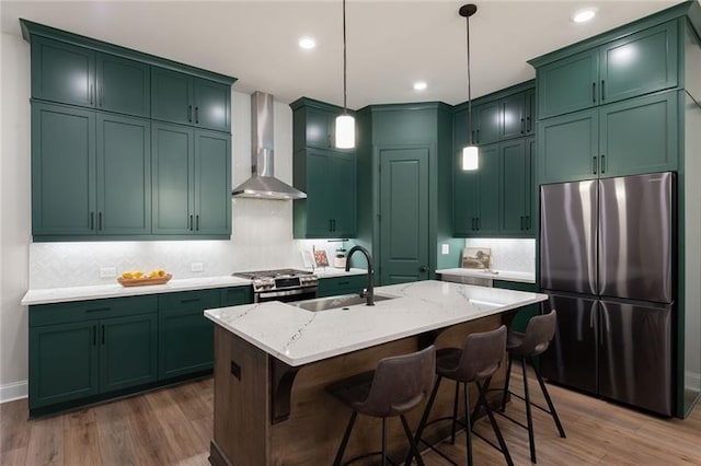 kitchen with wall chimney exhaust hood, sink, pendant lighting, stainless steel appliances, and light stone countertops