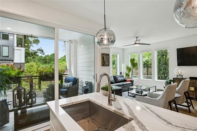 kitchen featuring decorative light fixtures, white cabinetry, stainless steel appliances, and a kitchen island with sink