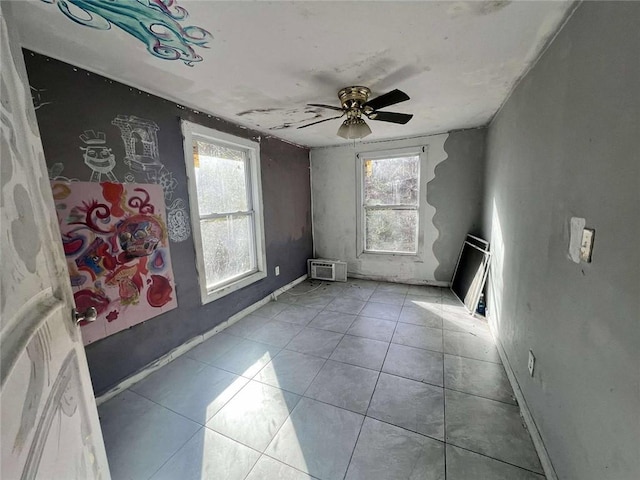 tiled empty room featuring a wall mounted air conditioner, ceiling fan, and a wealth of natural light