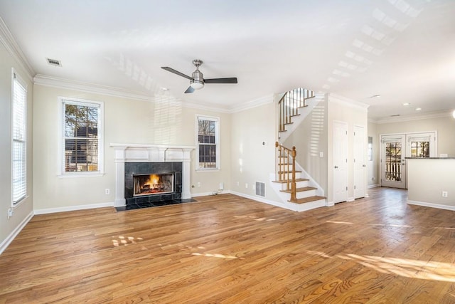 unfurnished living room with ceiling fan, light hardwood / wood-style floors, ornamental molding, and a tiled fireplace