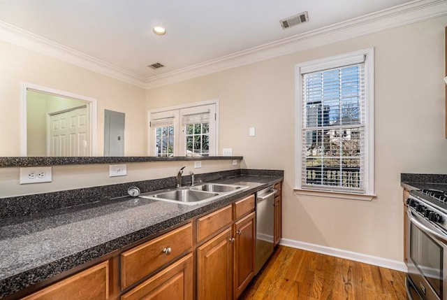 kitchen featuring sink, stainless steel appliances, crown molding, dark stone counters, and wood-type flooring