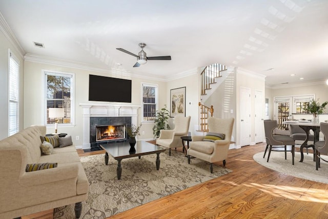 living room with crown molding, a fireplace, ceiling fan, and wood-type flooring