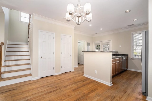 kitchen featuring pendant lighting, crown molding, appliances with stainless steel finishes, a notable chandelier, and light hardwood / wood-style floors