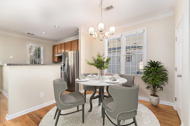 dining area with a healthy amount of sunlight, light hardwood / wood-style floors, a notable chandelier, and ornamental molding