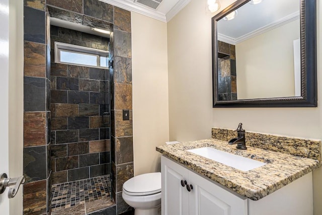 bathroom with crown molding, toilet, vanity, and tiled shower