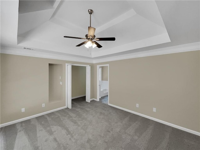 carpeted empty room with a tray ceiling, ceiling fan, and ornamental molding