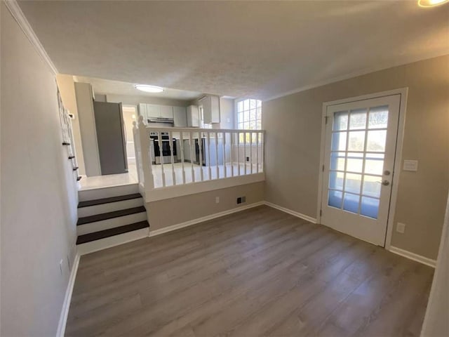 empty room featuring wood-type flooring, a wealth of natural light, and crown molding