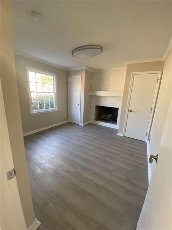 unfurnished living room featuring crown molding, a brick fireplace, and dark hardwood / wood-style flooring