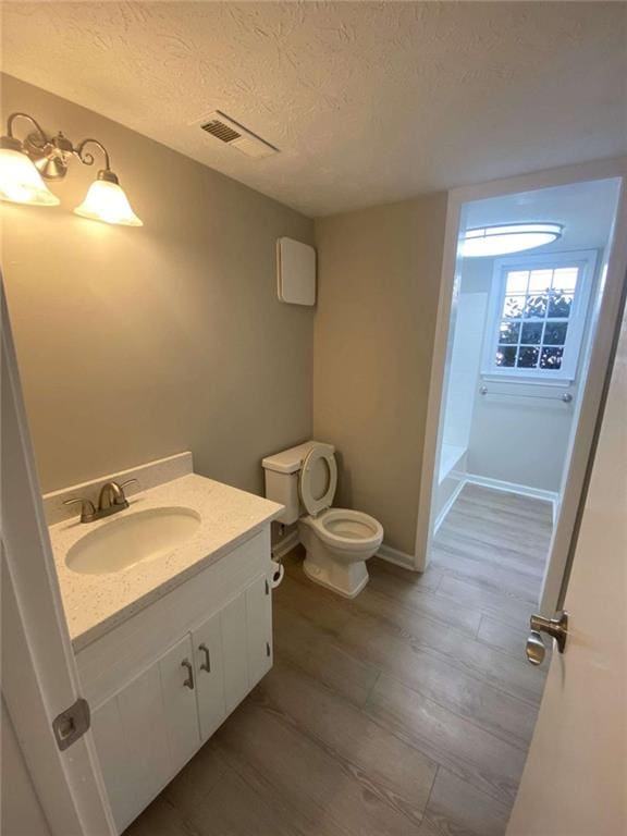 bathroom with vanity, toilet, and a textured ceiling