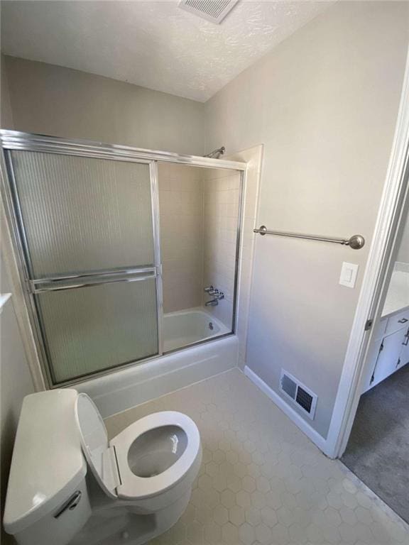 bathroom with bath / shower combo with glass door and toilet