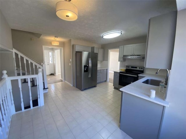 kitchen with stainless steel appliances, sink, gray cabinetry, and a textured ceiling