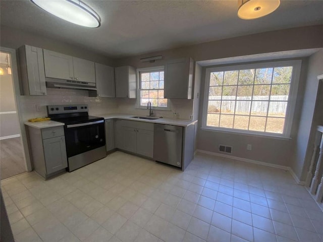 kitchen with gray cabinets, appliances with stainless steel finishes, sink, and backsplash