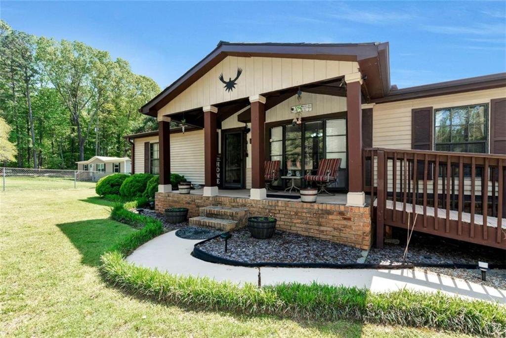 rear view of property featuring a lawn, fence, and covered porch