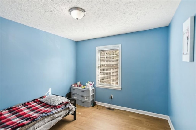 bedroom with a textured ceiling and light hardwood / wood-style floors