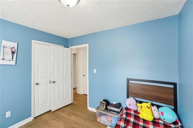 bedroom with a closet, light hardwood / wood-style flooring, and a textured ceiling