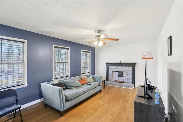 living room with hardwood / wood-style flooring, ceiling fan, and a fireplace