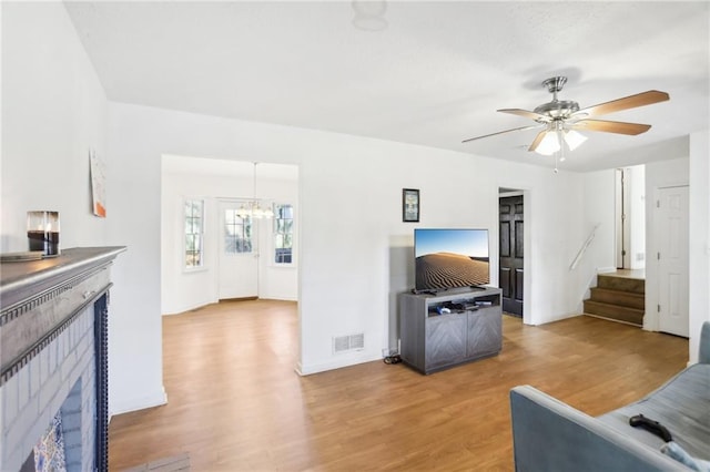 living room featuring ceiling fan with notable chandelier and hardwood / wood-style floors