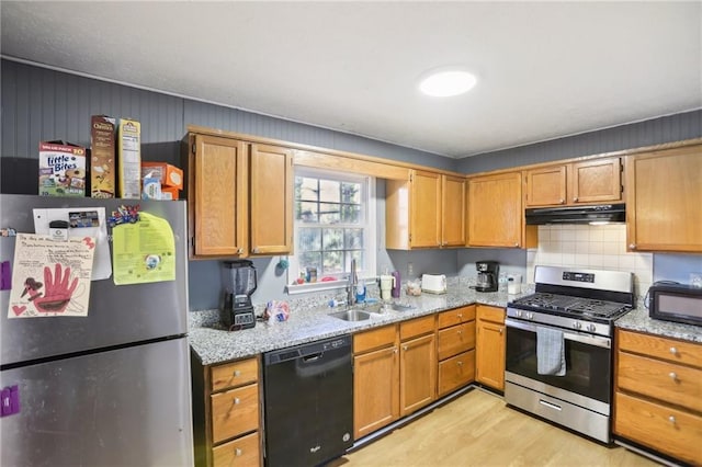 kitchen with sink, decorative backsplash, light hardwood / wood-style floors, black appliances, and light stone countertops