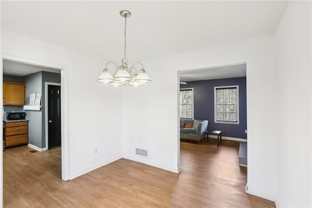 unfurnished dining area with hardwood / wood-style flooring and an inviting chandelier