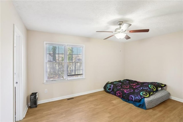 bedroom featuring ceiling fan, light hardwood / wood-style flooring, and a textured ceiling