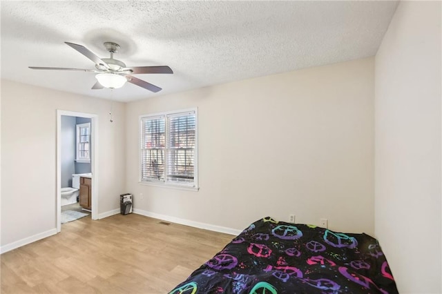 bedroom with ensuite bathroom, ceiling fan, a textured ceiling, and light hardwood / wood-style flooring