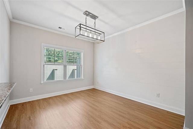 unfurnished dining area featuring wood finished floors, visible vents, baseboards, crown molding, and a notable chandelier