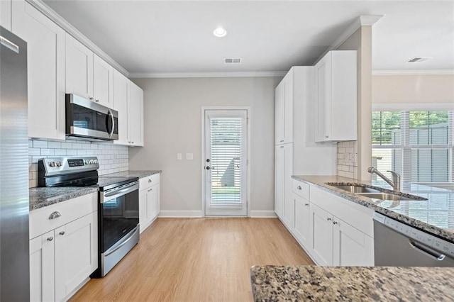 kitchen with light stone counters, visible vents, a sink, ornamental molding, and stainless steel appliances