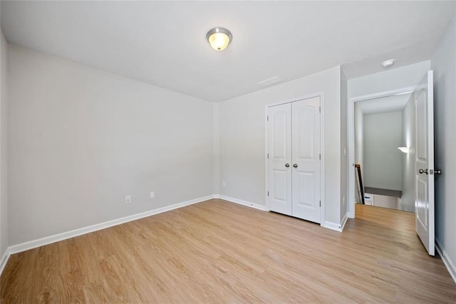 unfurnished bedroom featuring light wood-style floors, a closet, and baseboards