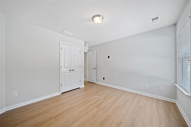 spare room with wood finished floors, visible vents, and baseboards