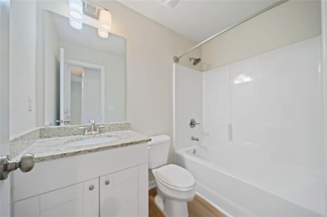 full bath with tub / shower combination, toilet, wood finished floors, and vanity