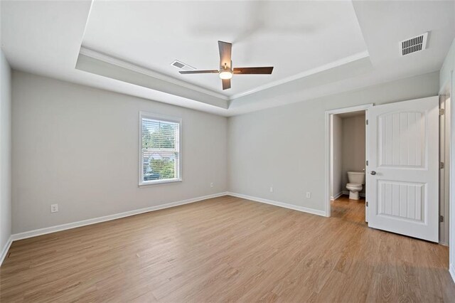 unfurnished bedroom with a raised ceiling, baseboards, visible vents, and light wood-type flooring