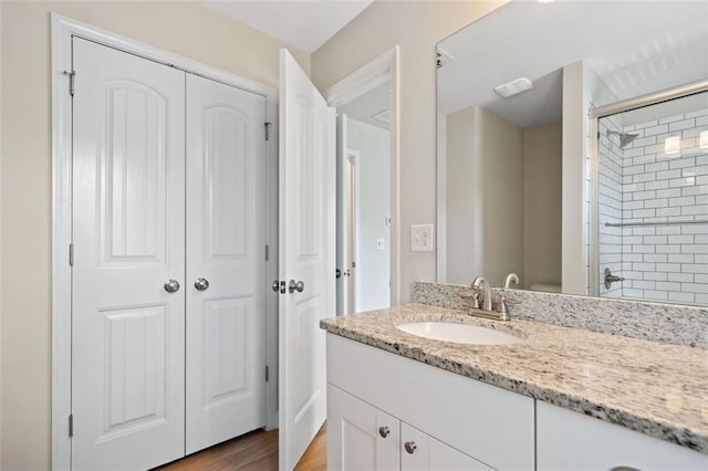 full bath with an enclosed shower, vanity, and wood finished floors