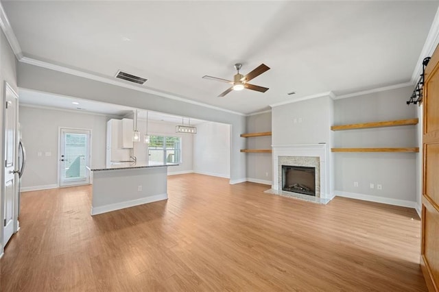 unfurnished living room featuring visible vents, crown molding, a fireplace with flush hearth, light wood-type flooring, and a ceiling fan