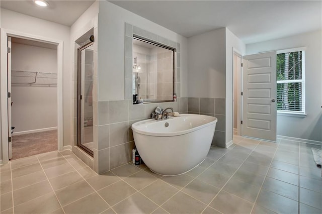 297 Delta Dr, Mcdonough, GA 30252 - bathroom with tile patterned flooring, a shower stall, a walk in closet, a freestanding tub, and baseboards