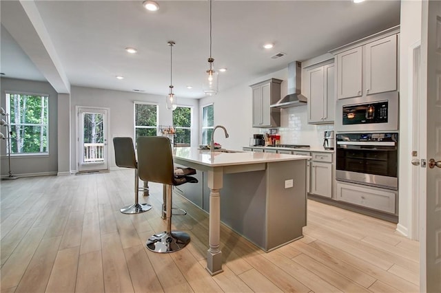 297 Delta Dr, Mcdonough, GA 30252 - kitchen featuring wall chimney exhaust hood, gray cabinets, an island with sink, healthy amount of natural light, and recessed lighting