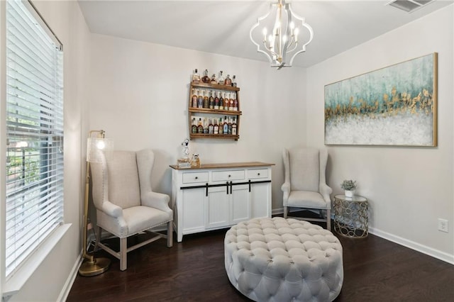 sitting room with bar area, dark hardwood / wood-style flooring, and a notable chandelier