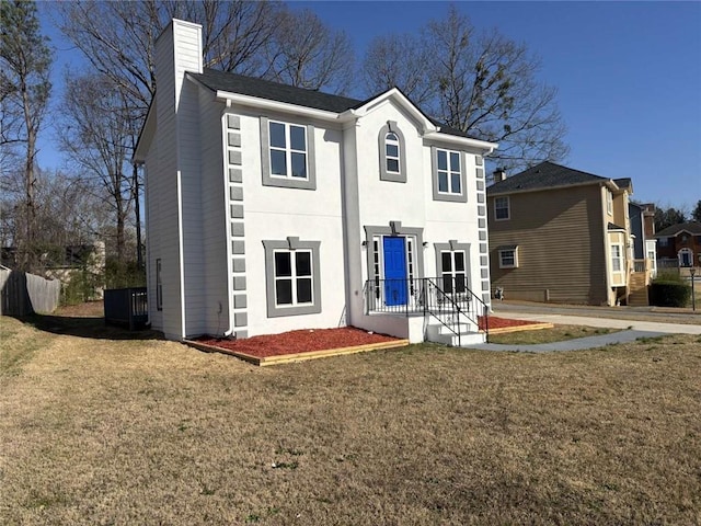 rear view of house featuring stucco siding, a lawn, central AC, and a chimney