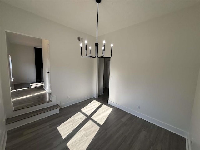 unfurnished dining area featuring an inviting chandelier, baseboards, visible vents, and dark wood-type flooring