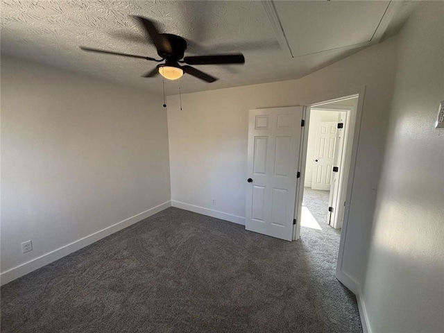 empty room with a textured ceiling, baseboards, dark carpet, and ceiling fan